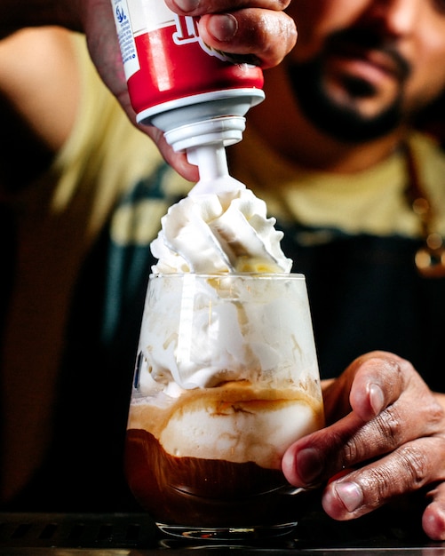 Photo gratuite vue de face barman prépare un dessert à la crème fouettée