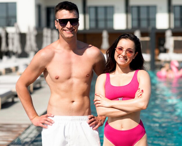 Vue de face d'un beau couple au bord de la piscine