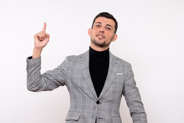 Vue de face beau mâle en costume pointant au plafond debout sur fond blanc