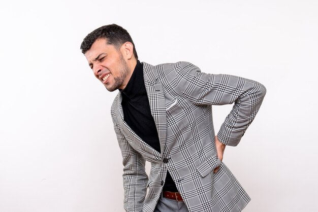 Vue de face beau mâle en costume tenant son dos avec douleur debout sur fond blanc