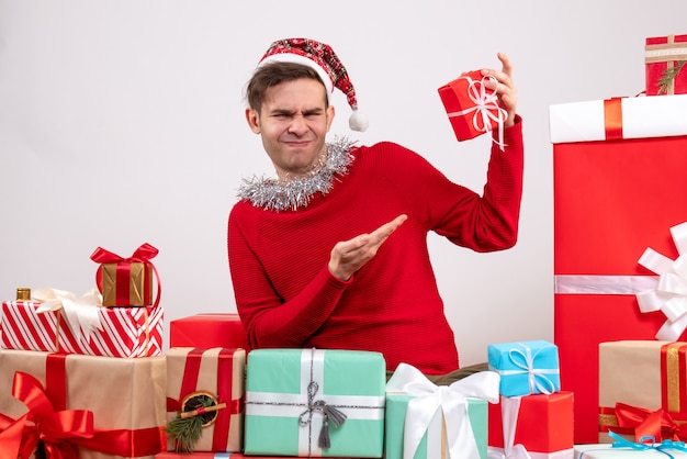 Vue de face bel homme avec chapeau snata assis autour de cadeaux de Noël