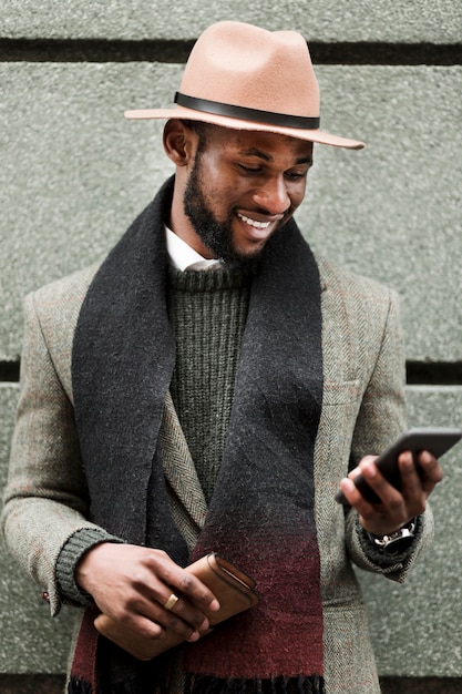 Vue de face bel homme en veste grise en regardant son téléphone