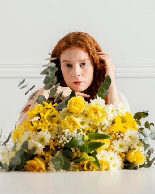 Vue de face de la belle femme posant avec bouquet de fleurs de printemps