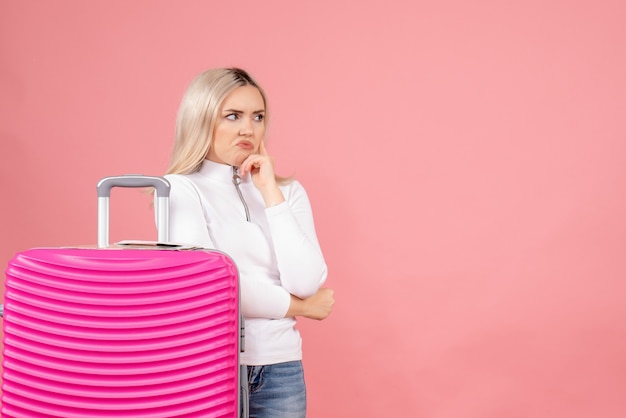 Vue de face belle femme avec valise rose penser à quelque chose