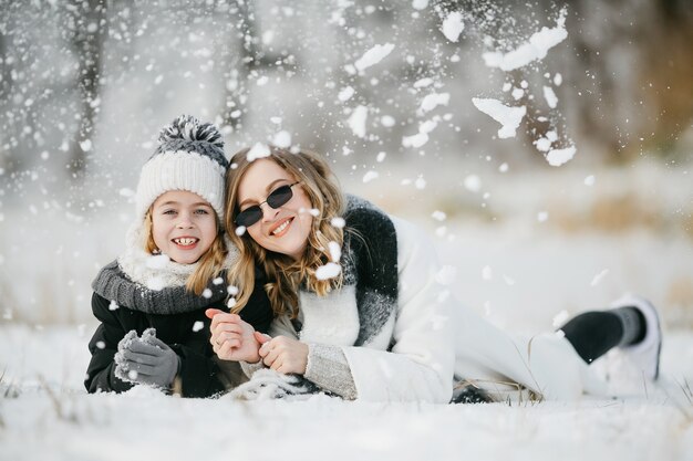 Vue de face de la belle mère et de sa petite fille adorable allongée sur la neige