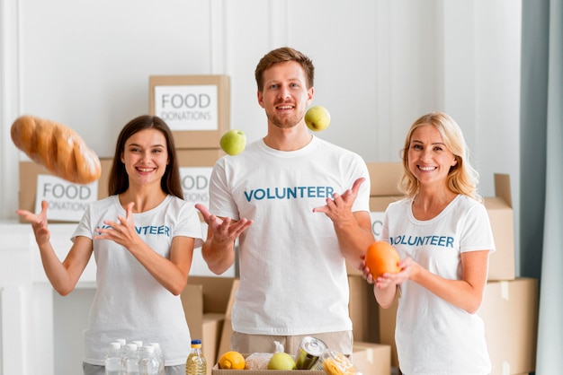 Vue de face de bénévoles smiley aidant avec des dons alimentaires