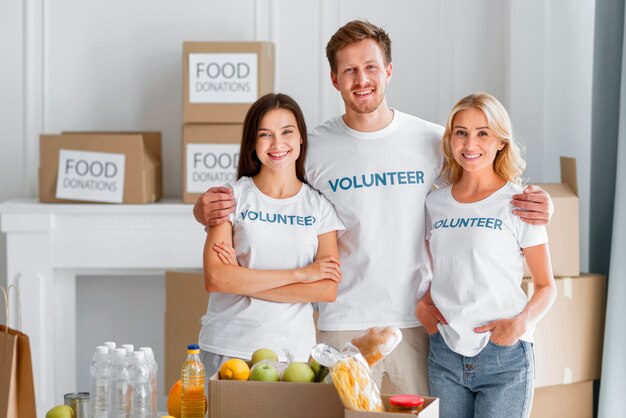 Vue de face des bénévoles smiley posant avec des dons alimentaires