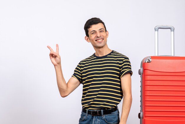 Vue de face béni jeune homme avec t-shirt rayé faisant signe de la victoire