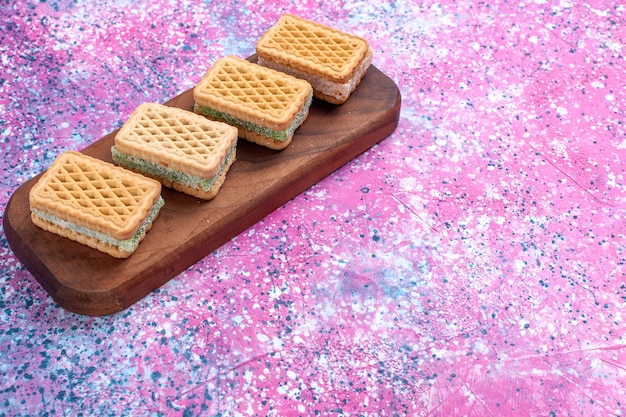 Photo gratuite vue de face biscuits gaufres avec garniture de crème aux fruits sur fond rose.