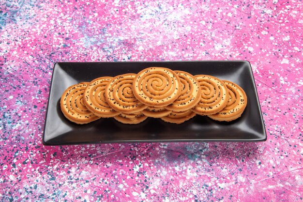 Vue de face biscuits sucrés délicieux petits biscuits à l'intérieur de forme noire sur un bureau rose clair.