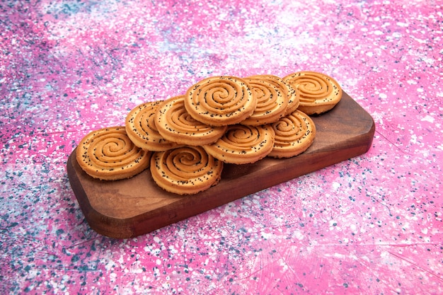 Vue de face des biscuits sucrés ronds bordés sur le fond rose.