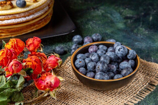 Vue de face bleuets frais avec un délicieux gâteau au miel surface sombre