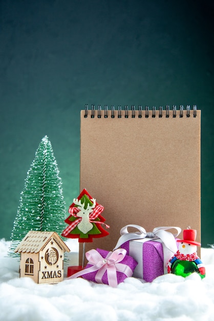 Vue de face bloc-notes jouets petits cadeaux mini arbre de Noël mini maison en bois sur une surface isolée verte