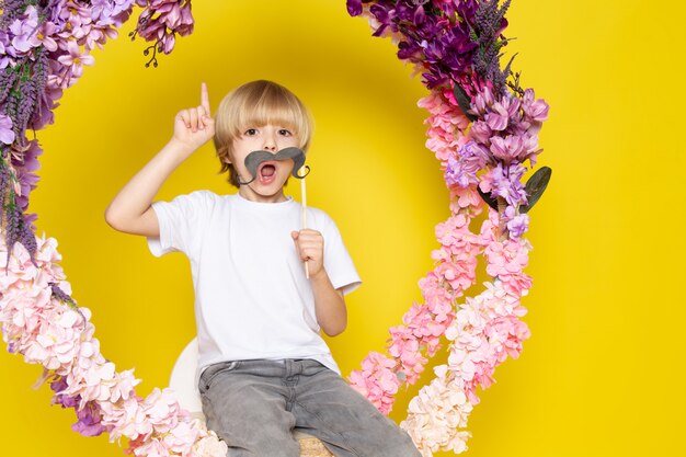 Une vue de face blonde kid drôle en t-shirt blanc sur l'espace jaune