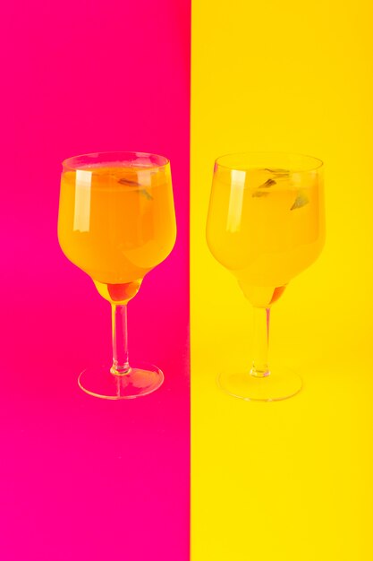 Une vue de face de boisson au citron glaçage frais à l'intérieur de verres isolés sur le fond jaune-rose boisson cocktail d'été