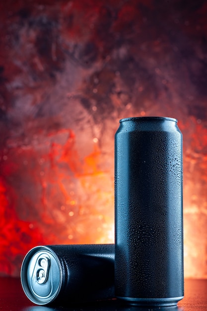 Vue de face boisson énergisante en canettes sur l'obscurité de photo d'alcool de boisson rouge