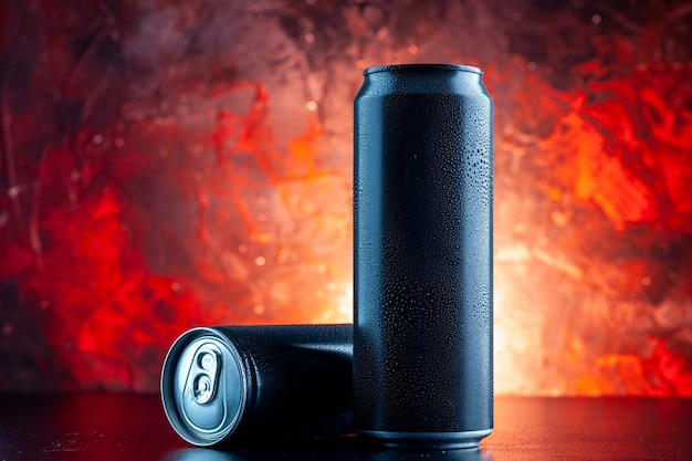 Vue de face boisson énergisante en canettes sur l'obscurité de photo d'alcool de boisson rouge