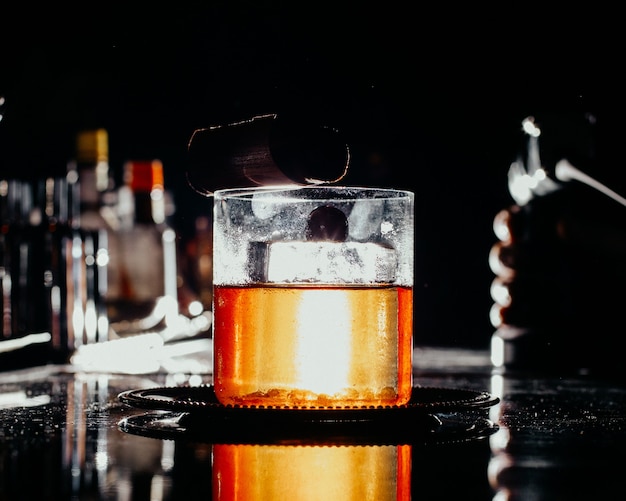 Photo gratuite une vue de face boisson glacée à l'intérieur du petit verre sur le bar sombre 24 boire du jus d'alcool bar à eau