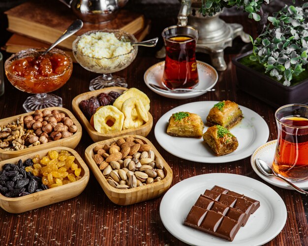 Vue de face bonbons service à thé barre de chocolat pistaches fruits secs baklava avec deux verres d'armudu