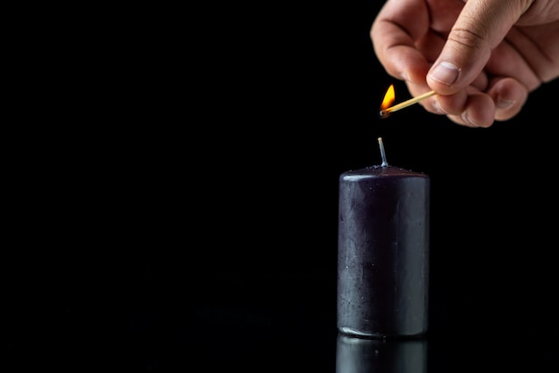 Vue de face de la bougie noire sur la surface sombre