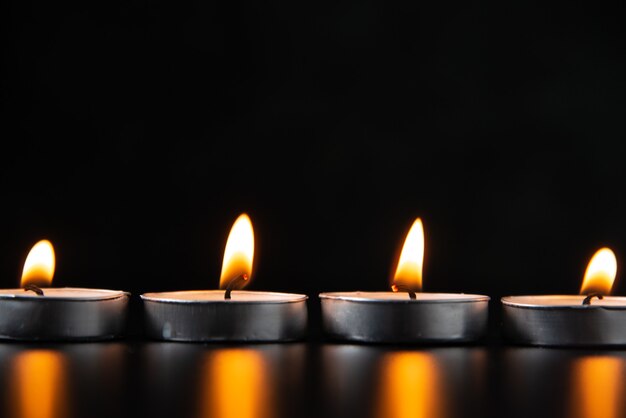 Vue de face des bougies allumées sur une surface sombre