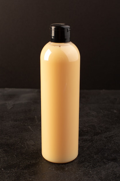 Une vue de face bouteille de shampooing en plastique de couleur crème peut avec capuchon noir isolé sur les cheveux de beauté cosmétiques fond sombre