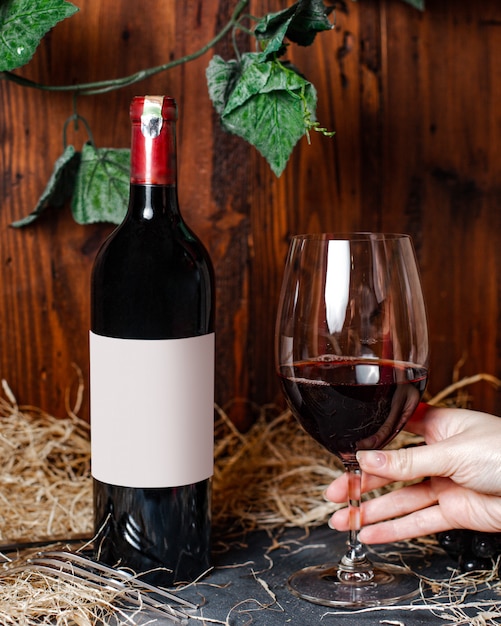 Une Vue De Face Bouteille De Vin Vin Rouge Avec Bouchon Bourgogne Avec Verre Et Feuilles Vertes Sur L'arrière-plan Cave à Alcool