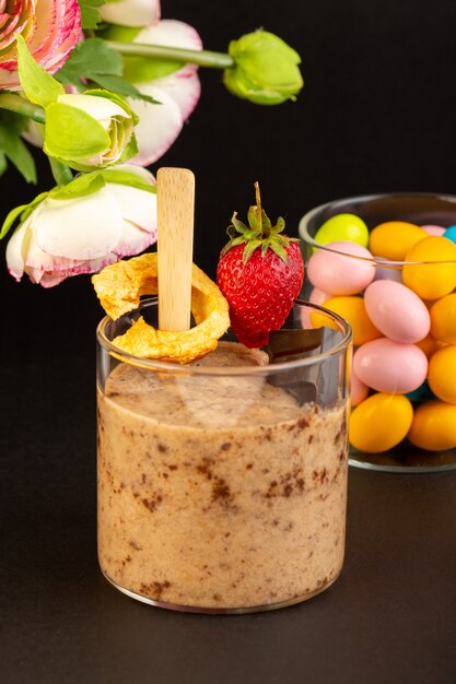 Une vue de face brown choco dessert savoureux délicieux sucré avec du café en poudre chocolat bar et fraise avec des bonbons sur le fond sombre doux dessert fraîcheur