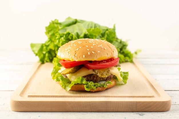 Une vue de face burger de poulet avec du fromage et de la salade verte sur le bureau en bois et sandwich repas de restauration rapide