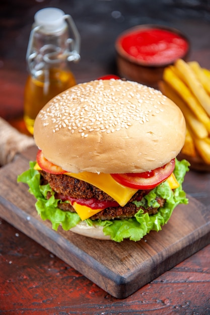 Vue de face burger de viande avec fromage tomates et salade sur fond sombre