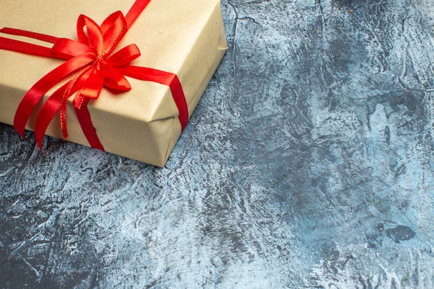 Vue de face cadeau de Noël attaché avec un arc rouge sur photo de vacances clair-foncé couleur de noël nouvel an espace libre