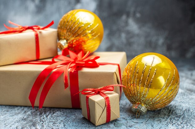 Vue de face des cadeaux de Noël attachés avec des arcs rouges et des jouets sur photo sombre-clair cadeau de nouvel an couleur de vacances noël