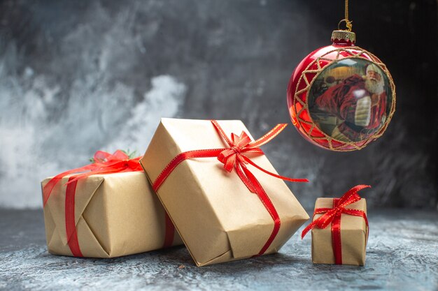 Vue de face des cadeaux de Noël attachés avec des arcs rouges sur photo de couleur claire-foncée cadeaux de Noël de vacances de nouvel an