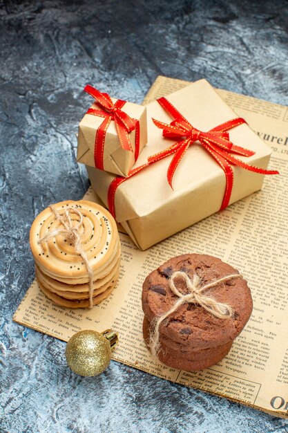 Vue de face des cadeaux de Noël avec des biscuits et des jouets sur une photo couleur cadeau clair-foncé vacances de noël du nouvel an