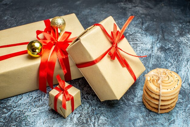 Vue de face des cadeaux de Noël avec des biscuits sucrés sur le cadeau photo de vacances clair-foncé couleur de noël nouvel an