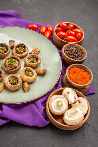 Vue de face des champignons cuits à l'intérieur de la plaque avec des assaisonnements sur un plat de tissu violet repas dîner aux champignons cuisson