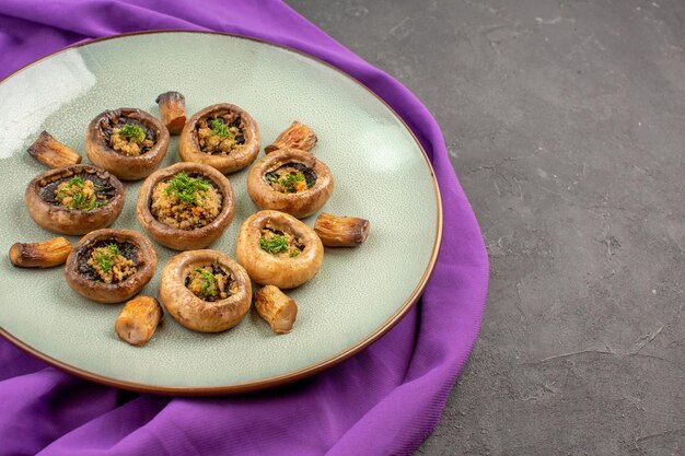 Vue de face des champignons cuits à l'intérieur de la plaque sur un plat de tissu violet repas champignons dîner cuisson