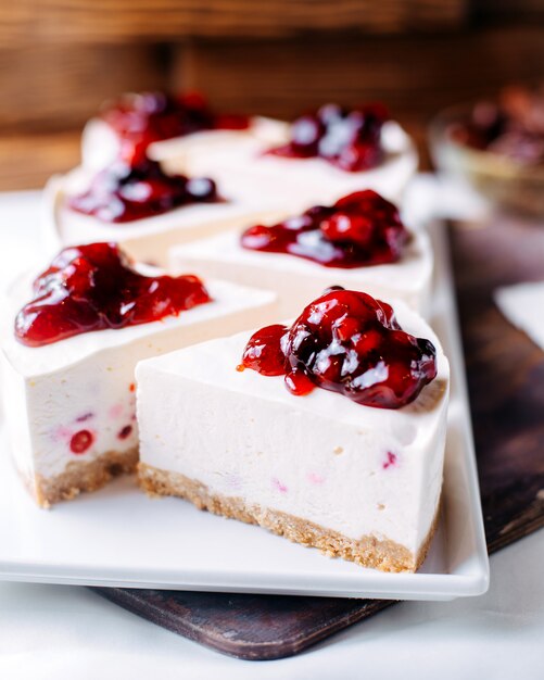 Vue de face cheesecake cerise délicieux à l'intérieur de la plaque blanche sur la surface brune