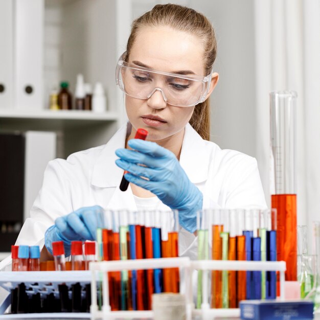 Vue de face de la chercheuse avec des gants et des tubes à essai dans le laboratoire