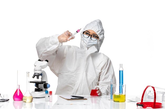 Vue de face chimiste en combinaison de protection spéciale travaillant avec des solutions sur fond blanc laboratoire de virus de chimie covid