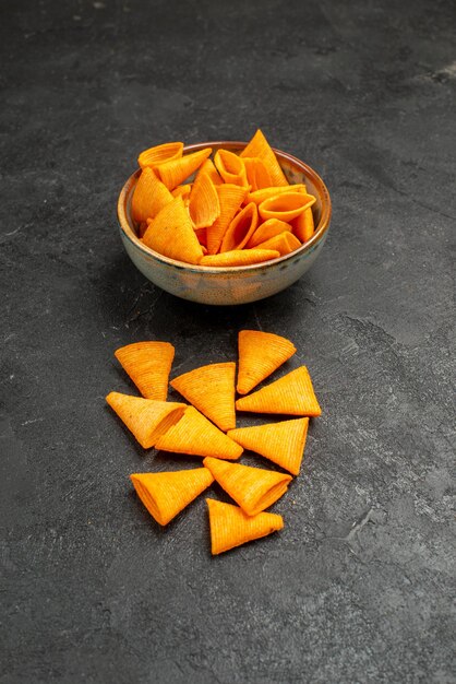 Vue de face des cips au fromage orange avec du poivre épicé sur fond sombre couleur maïs pomme de terre collation