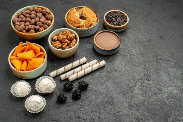 Vue de face des cips orange avec des noix sucrées et des flocons de chocolat sur fond gris foncé collation repas petit-déjeuner noix