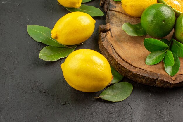 Vue de face de citrons frais sur plancher sombre fruits lime agrumes aigre