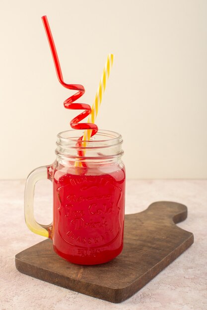 Une vue de face cocktail de cerises rouges avec des pailles à l'intérieur peut sur le bureau rose boire du jus de fruits de couleur