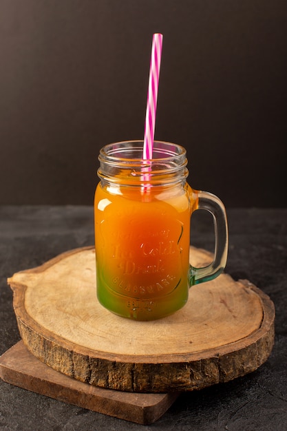 Une vue de face cocktail froid coloré à l'intérieur du verre peut avec de la paille colorée isolé sur le bureau en bois et sombre