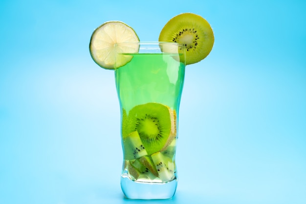 Une vue de face cocktail de fruits frais avec des tranches de fruits frais refroidissement par glace sur bleu, boisson jus de fruits cocktail couleur de fruits