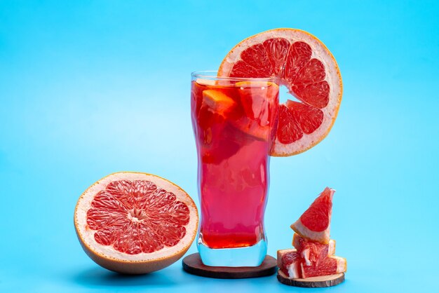 Une vue de face cocktail de fruits frais avec des tranches de fruits frais refroidissement par glace sur bleu, boisson jus de fruits cocktail couleur de fruits