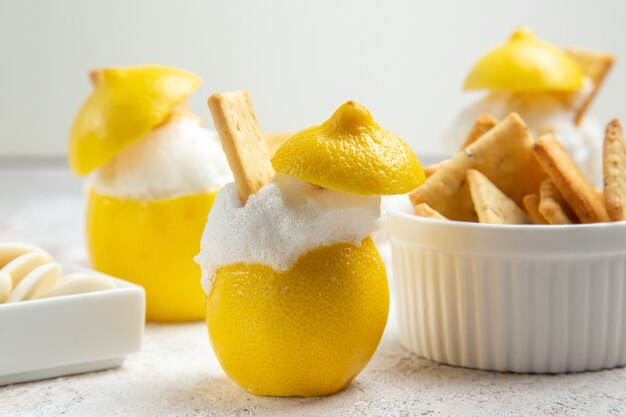 Vue de face des cocktails au citron avec de la glace et des craquelins sur du jus de cocktail aux agrumes de table blanche