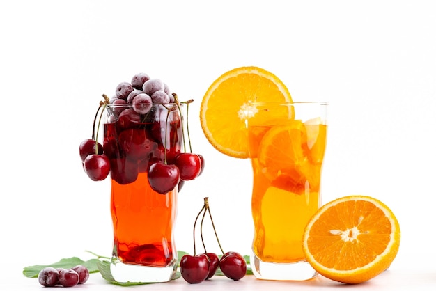 Une vue de face des cocktails de fruits avec des cerises fraîches et du refroidissement de glace slicec orange sur blanc, boire du jus de fruits cocktail couleur de fruits