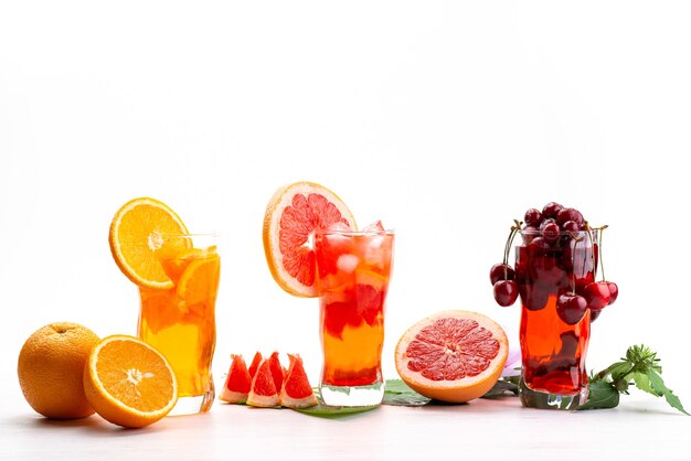 Une vue de face des cocktails de fruits frais avec des tranches de fruits frais refroidissement par glace sur blanc, boire du jus de fruits cocktail couleur de fruits